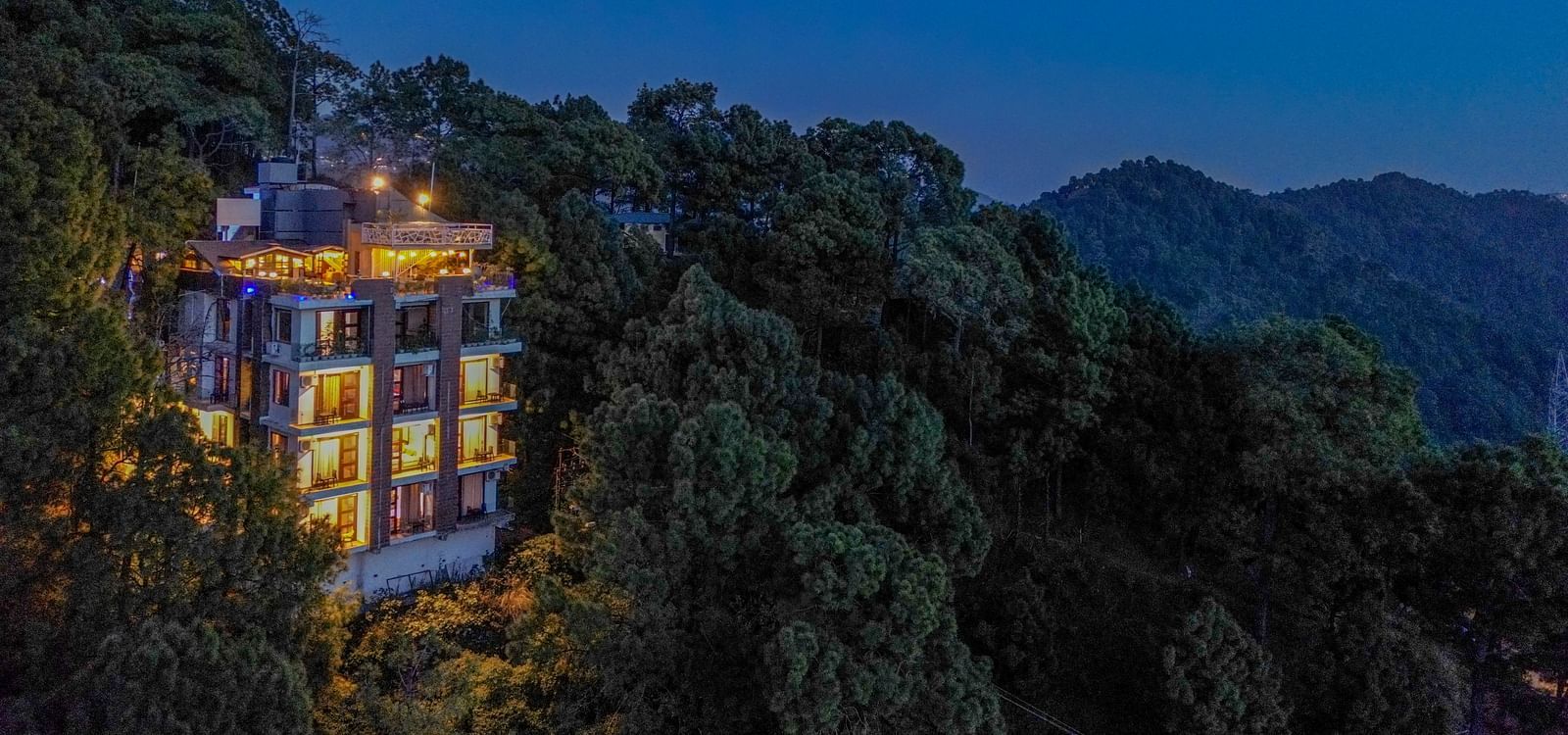 A drone shot of DLS Whispering Winds surrounded by tress, mountains and lush greenery